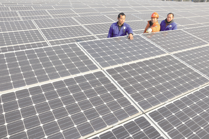 圖為光伏電站技術(shù)人員巡查太陽能發(fā)電設備